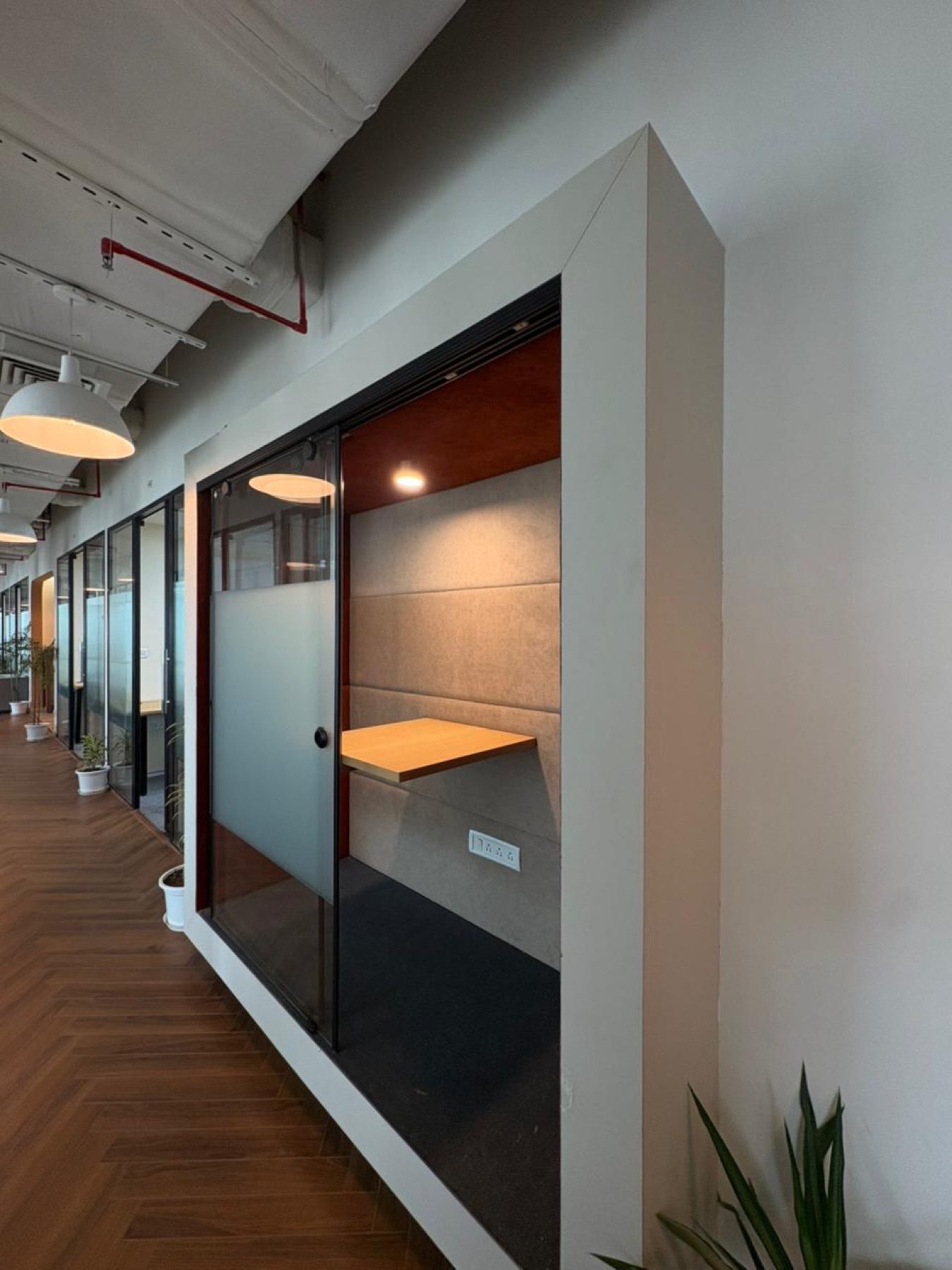 Private focus booth at Limelight Coworks with a built-in desk and glass sliding door