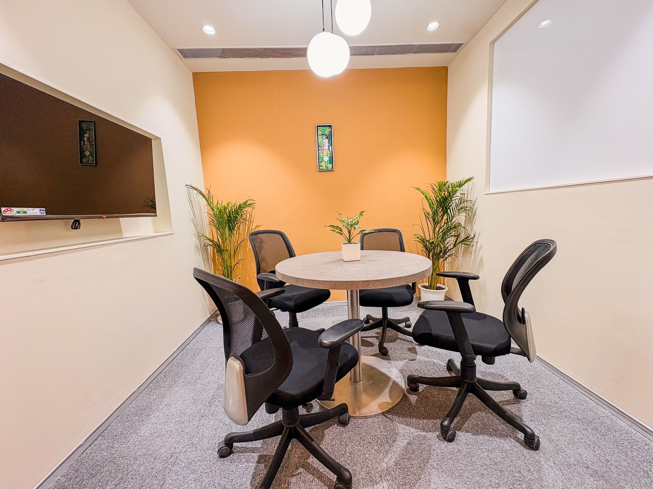 Small meeting room at Limelight Coworks with a round table, plants, and acoustic privacy